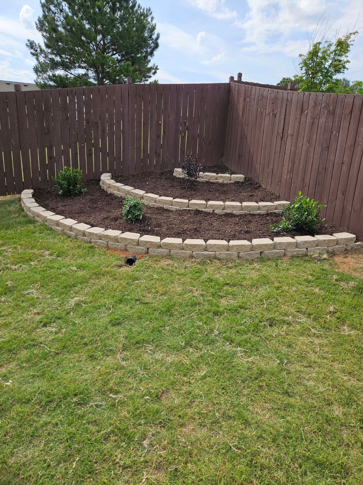 A backyard with a fence and a garden in the middle of it.