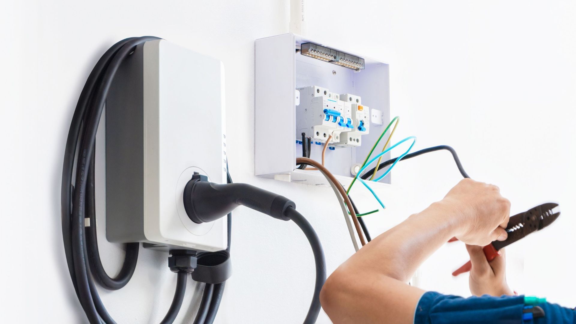 A man is working on an electrical box on a wall.