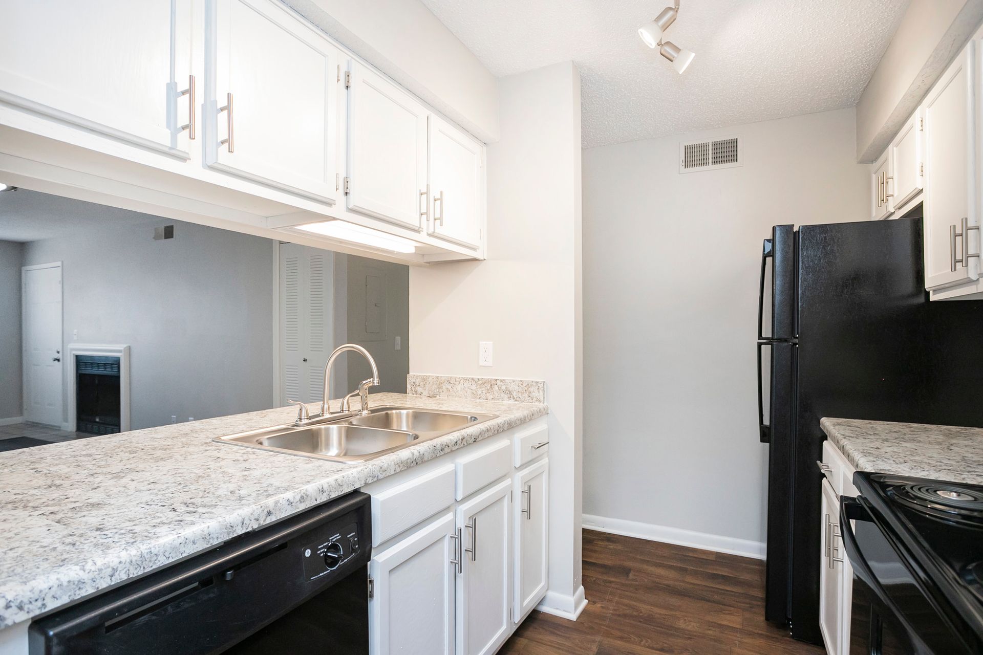A bright kitchen with white cabinets, speckled granite countertops, and black appliances.