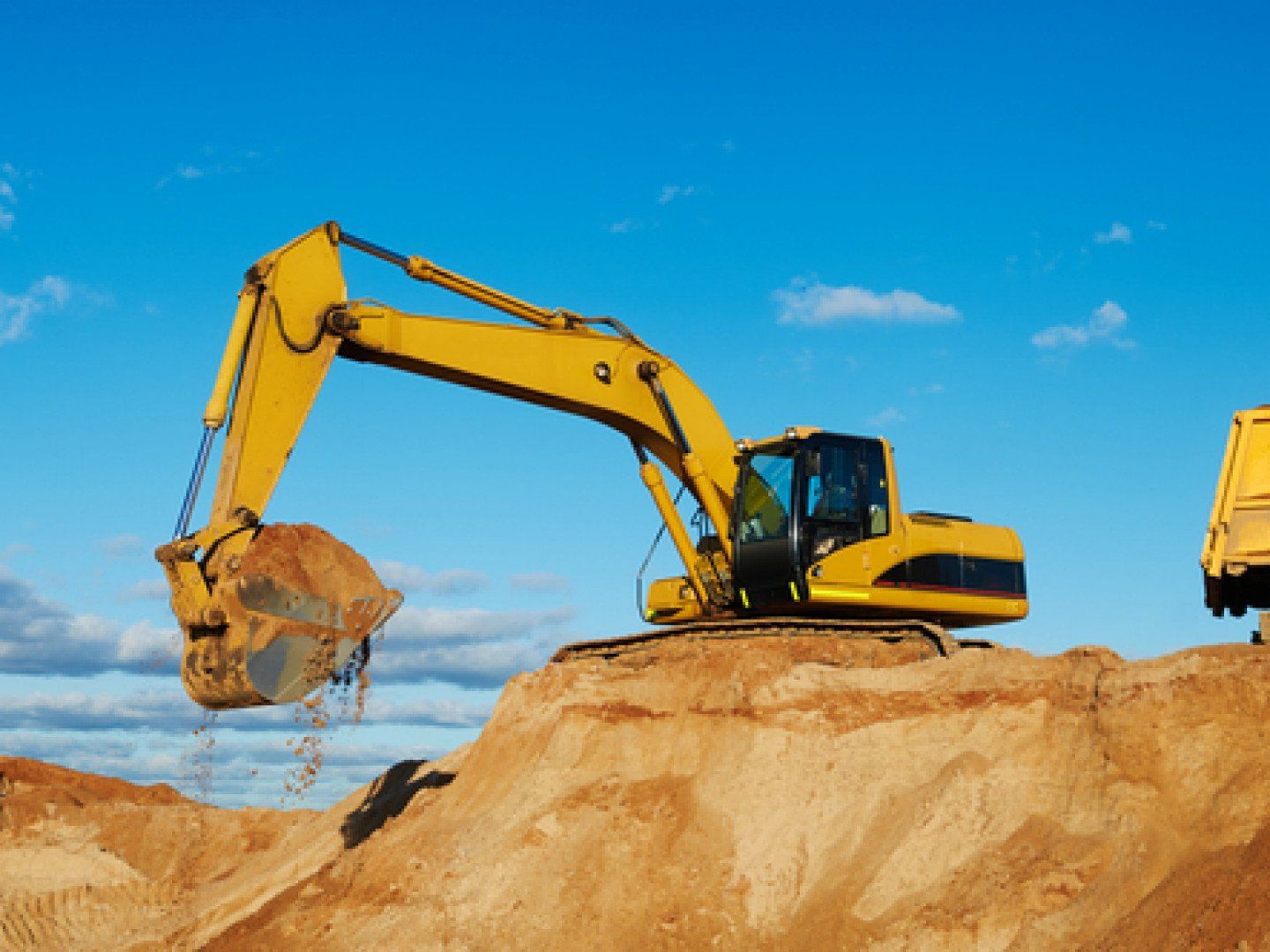 excavator machine loading dumper truck at sand quarry