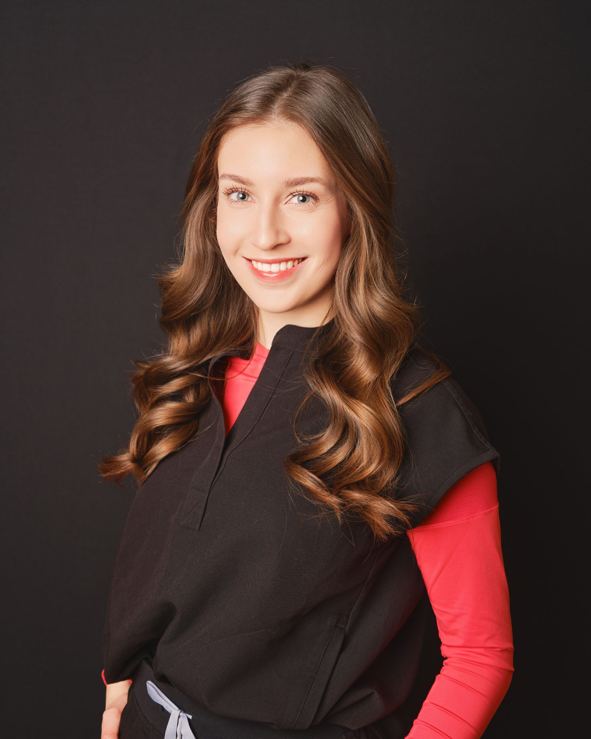 Une femme portant un haut noir et une chemise rouge sourit à la caméra.