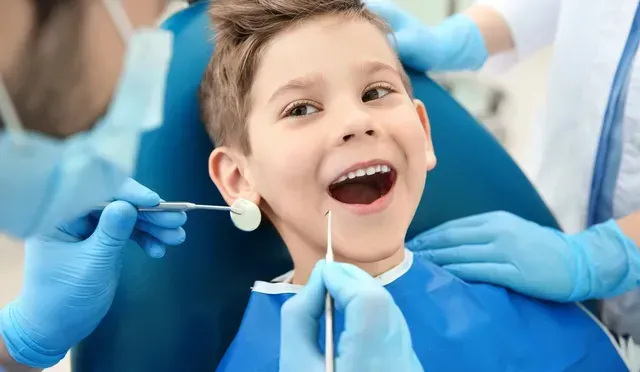 Un jeune garçon est assis dans un fauteuil dentaire pendant qu un dentiste examine ses dents.