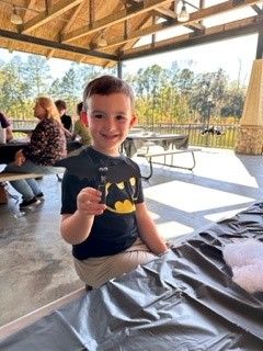 Smiling child holding a snack at a picnic table under a covered pavilion