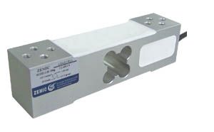 A metal block with a hole in the middle is sitting on a white surface.