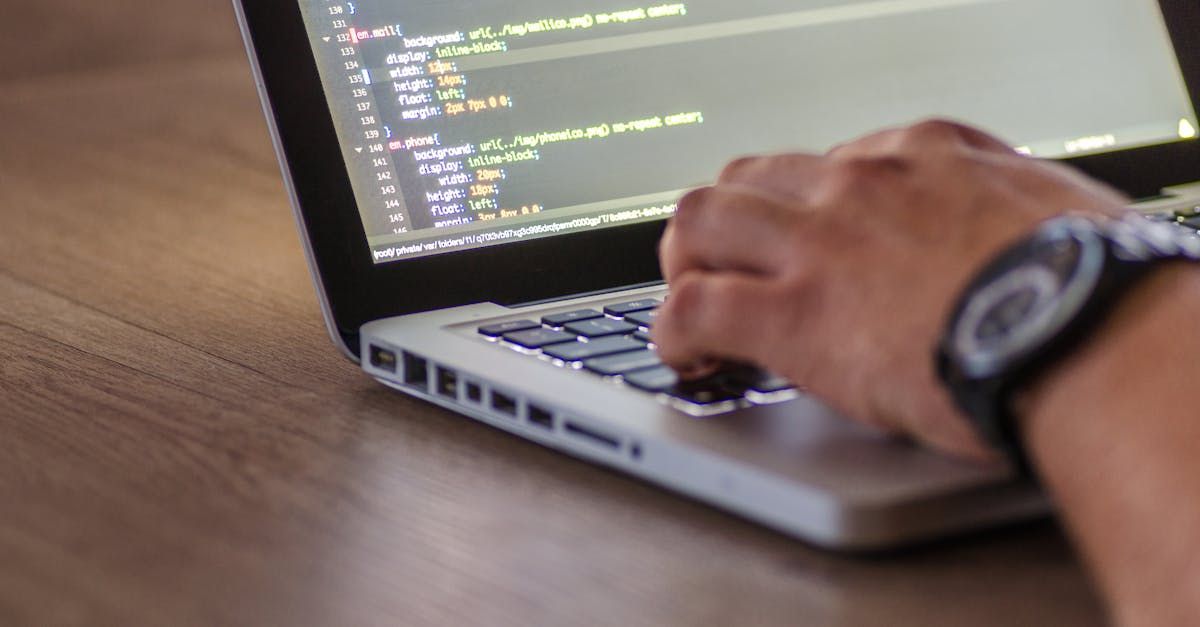 A person wearing a watch is typing on a laptop computer.