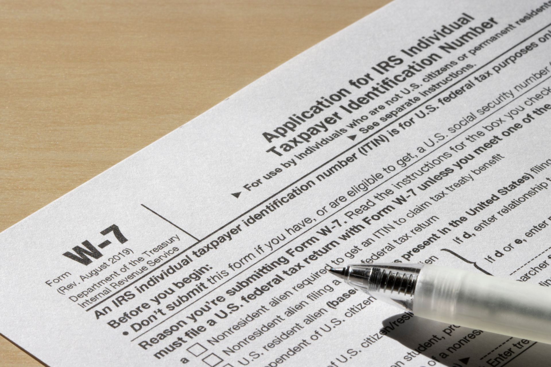 A pen sits on top of a w-7 tax form