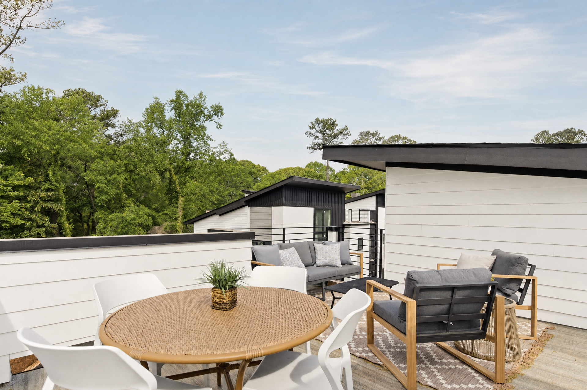 Outdoor patio with round table, white chairs, and lounge seating on a rooftop deck.