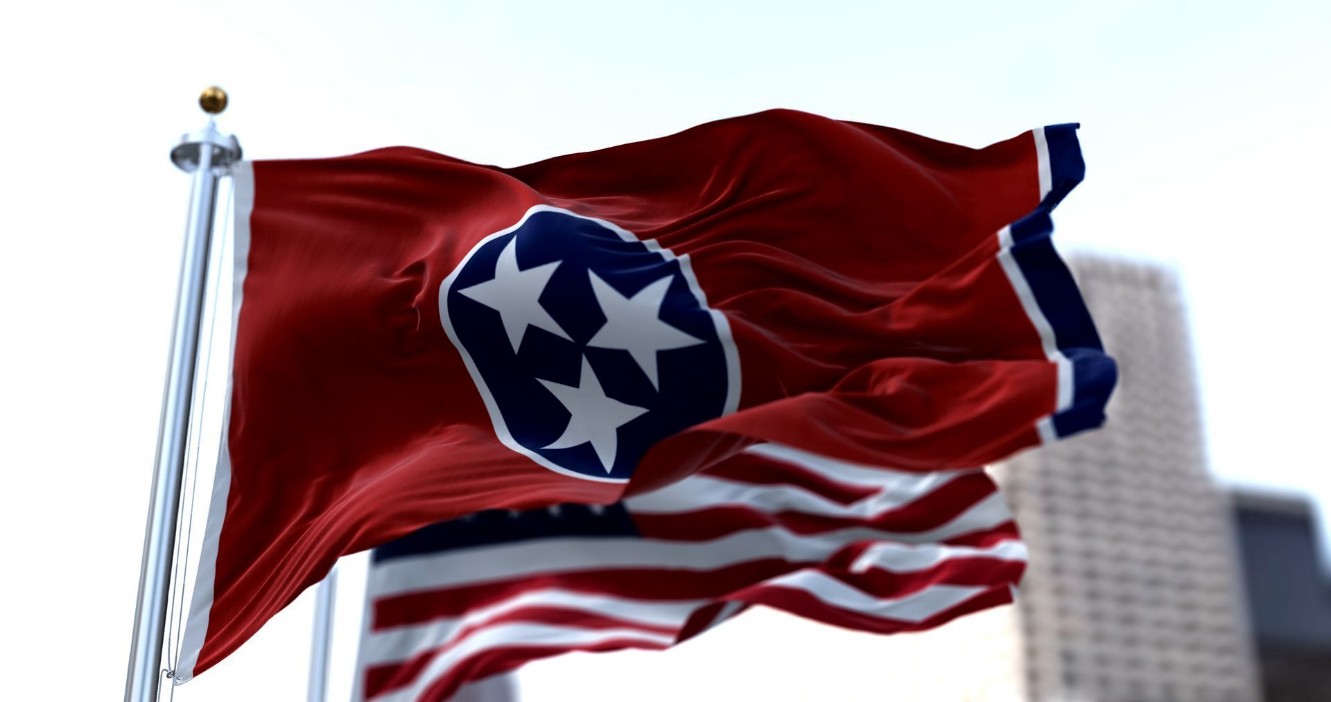 Two flags are waving in the wind in front of a building