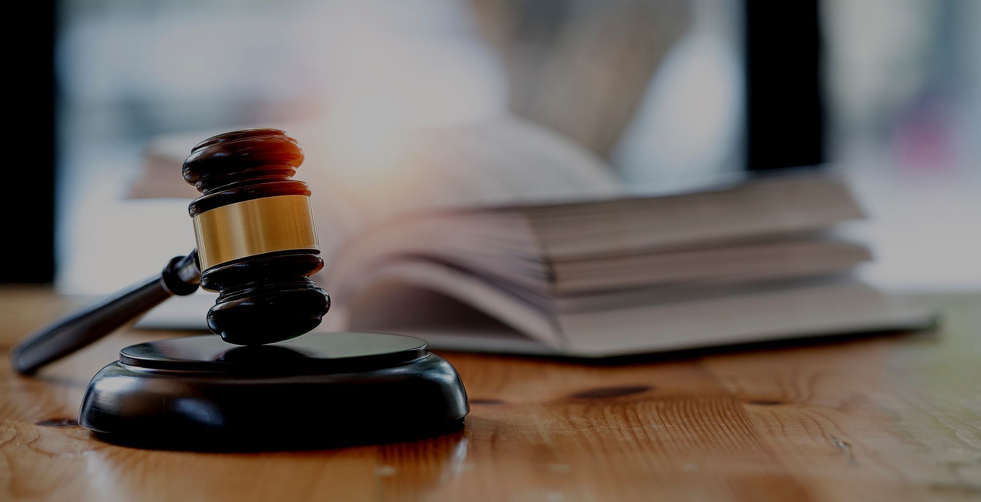 A judge 's gavel is sitting on a wooden table next to a stack of books.