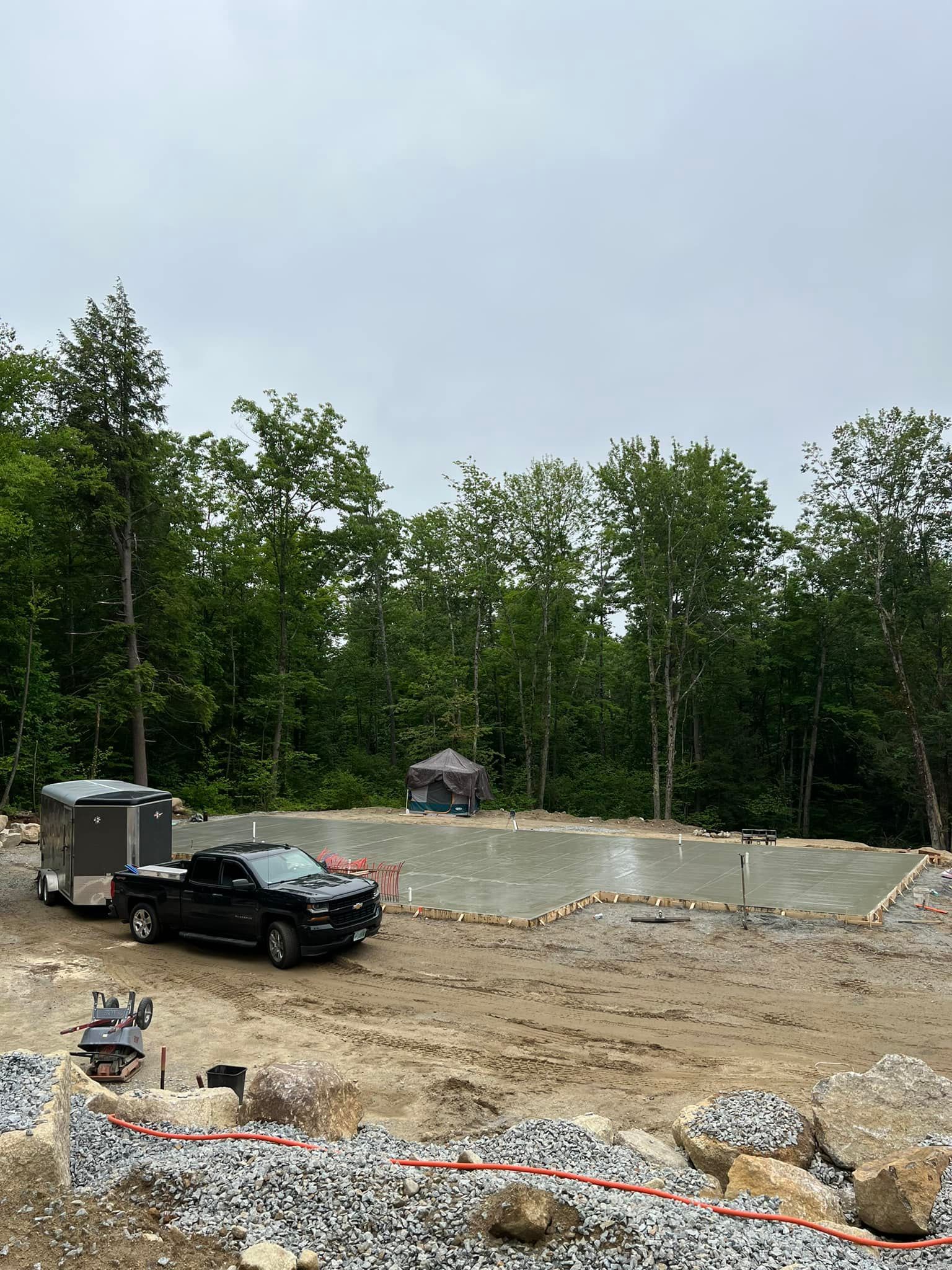 A truck is parked in a dirt lot next to a trailer.