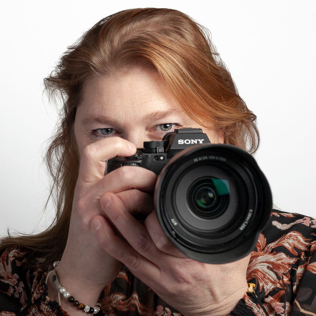 Vrouw houdt een Sony-camera voor haar oog, geconcentreerd op het maken van een foto.