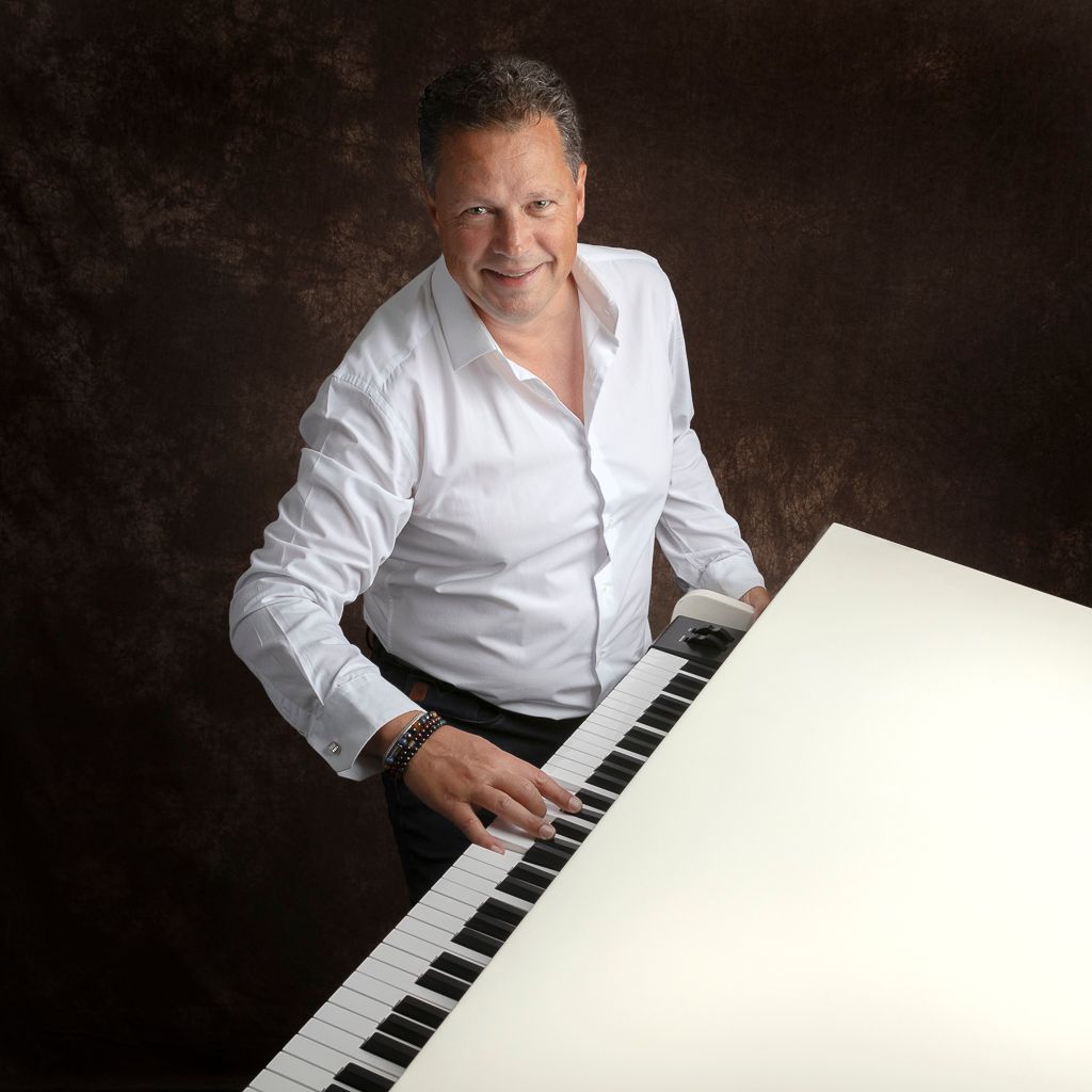 Man die op een keyboard piano speelt, lachend. donkere achtergrond