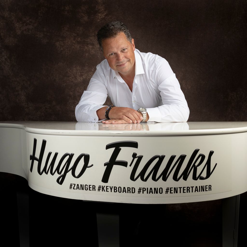 Een man leunt op een witte piano. Op de piano staat 