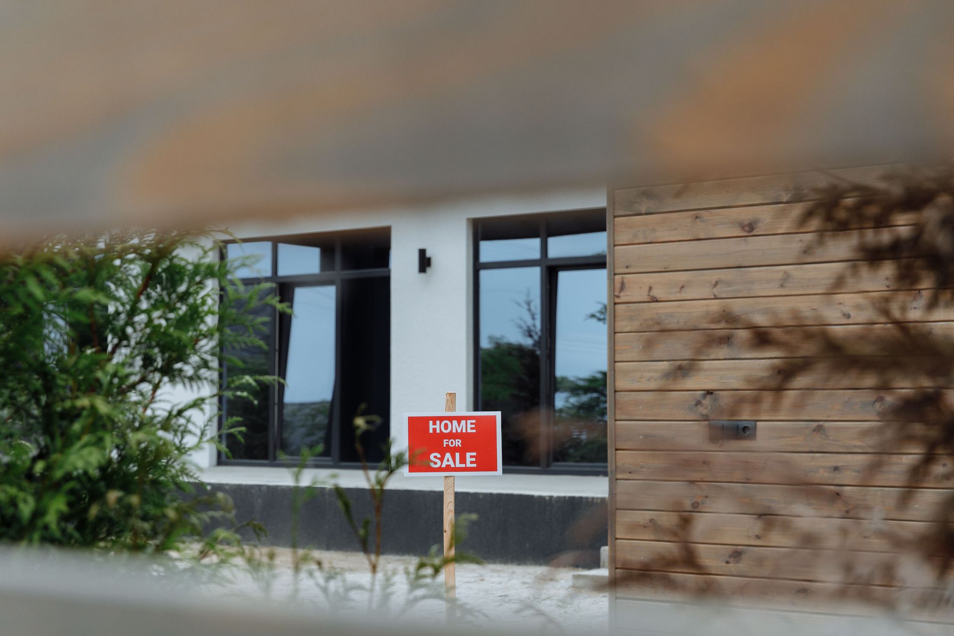 House exterior with a red “For Sale” sign by the front window.