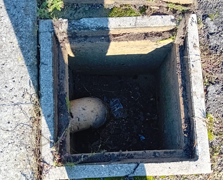 Pozzetto di drenaggio in cemento aperto con un tubo e acqua scura all'interno