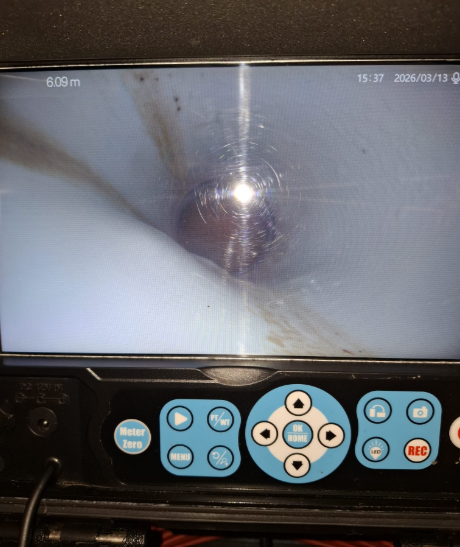 Sullo schermo di un dispositivo è visibile un oggetto scuro e sfocato, con pulsanti di controllo blu e bianchi sottostanti.