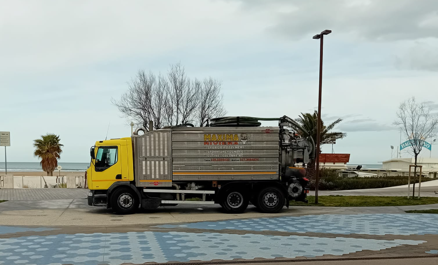 Camion giallo parcheggiato in riva al mare in una giornata nuvolosa.