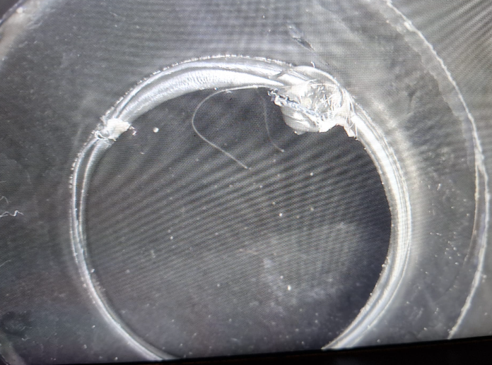 Primo piano di un anello di tessuto grigio strappato su una superficie scura e ruvida.