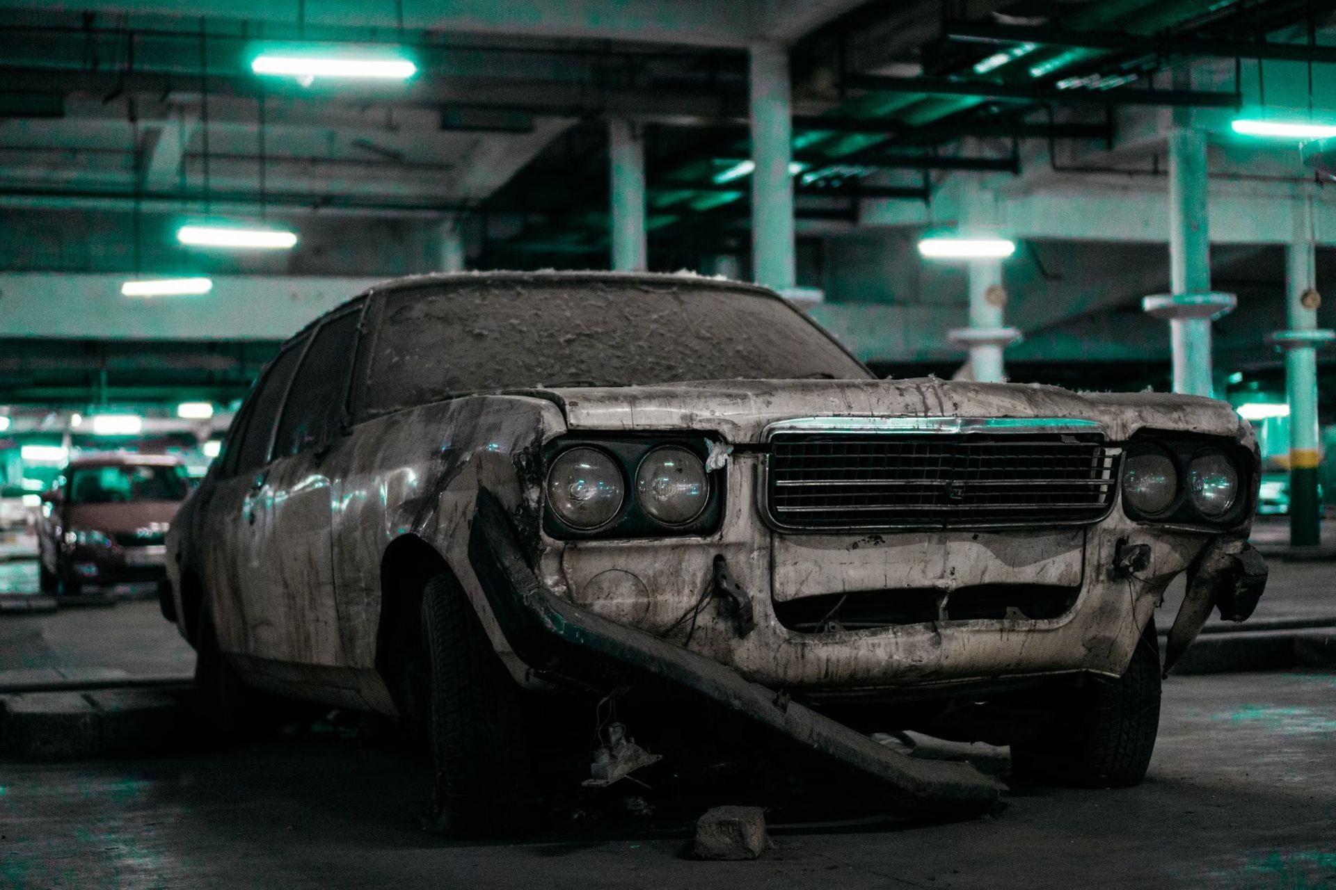 Dusty vintage car in a dim parking garage, covered in grime and debris.