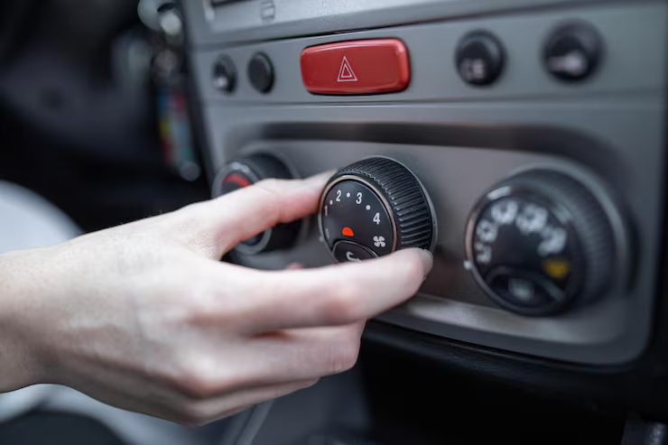 Hand turning a car's climate control dial, adjusting the fan speed.