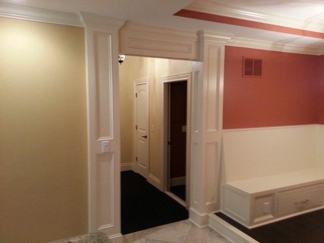 An interior view showing a white-trimmed arched doorway connecting a room with a built-in bench to a hallway.