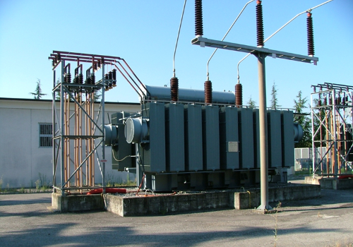 Grande sottostazione di trasformazione elettrica con linee elettriche e apparecchiature grigie all'esterno.