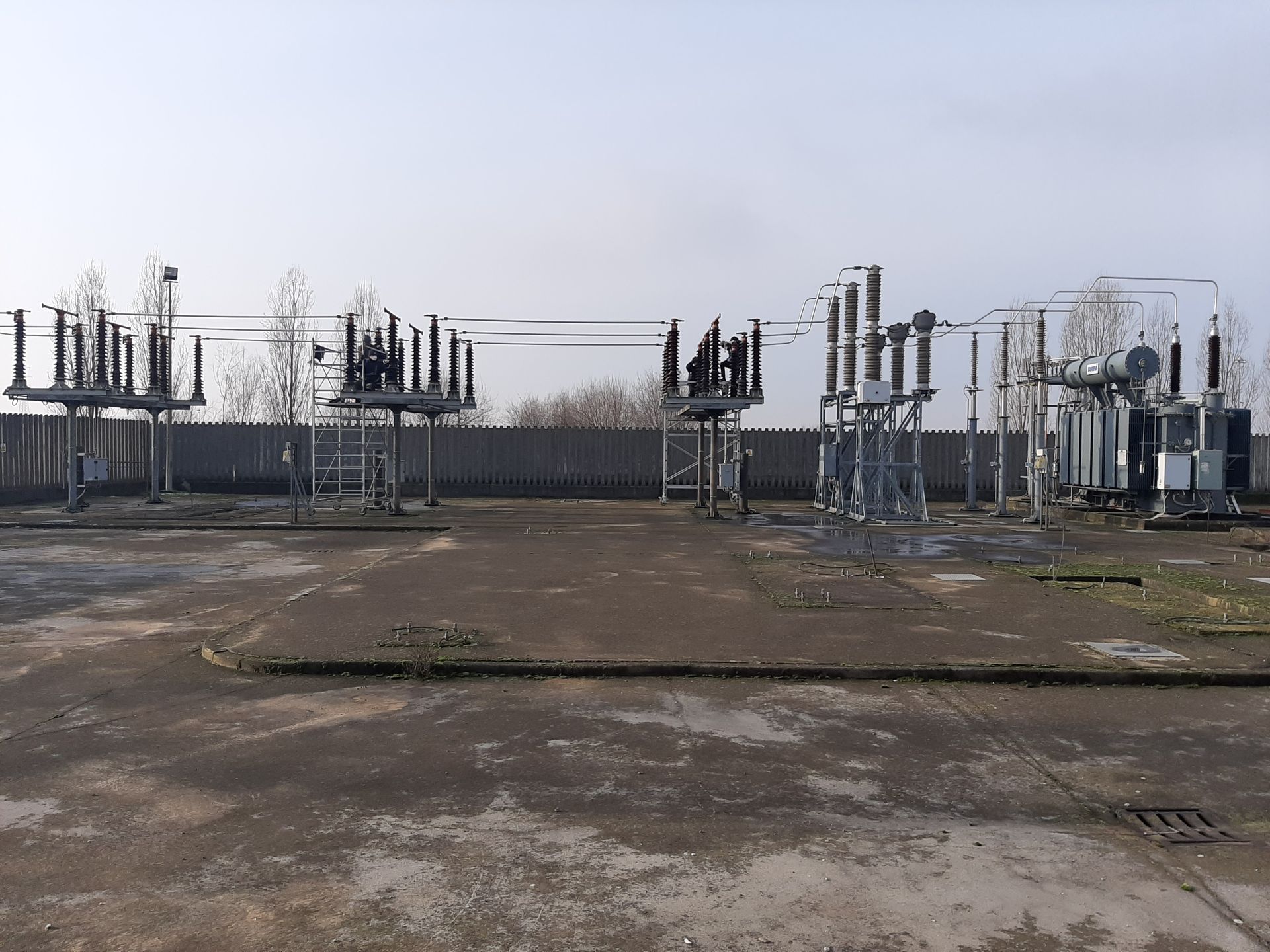Sottostazione elettrica industriale con trasformatori e linee elettriche su un lotto pianeggiante in cemento sotto un cielo sereno