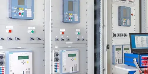 Quadri elettrici di controllo con display digitali e interruttori in un luminoso locale industriale.