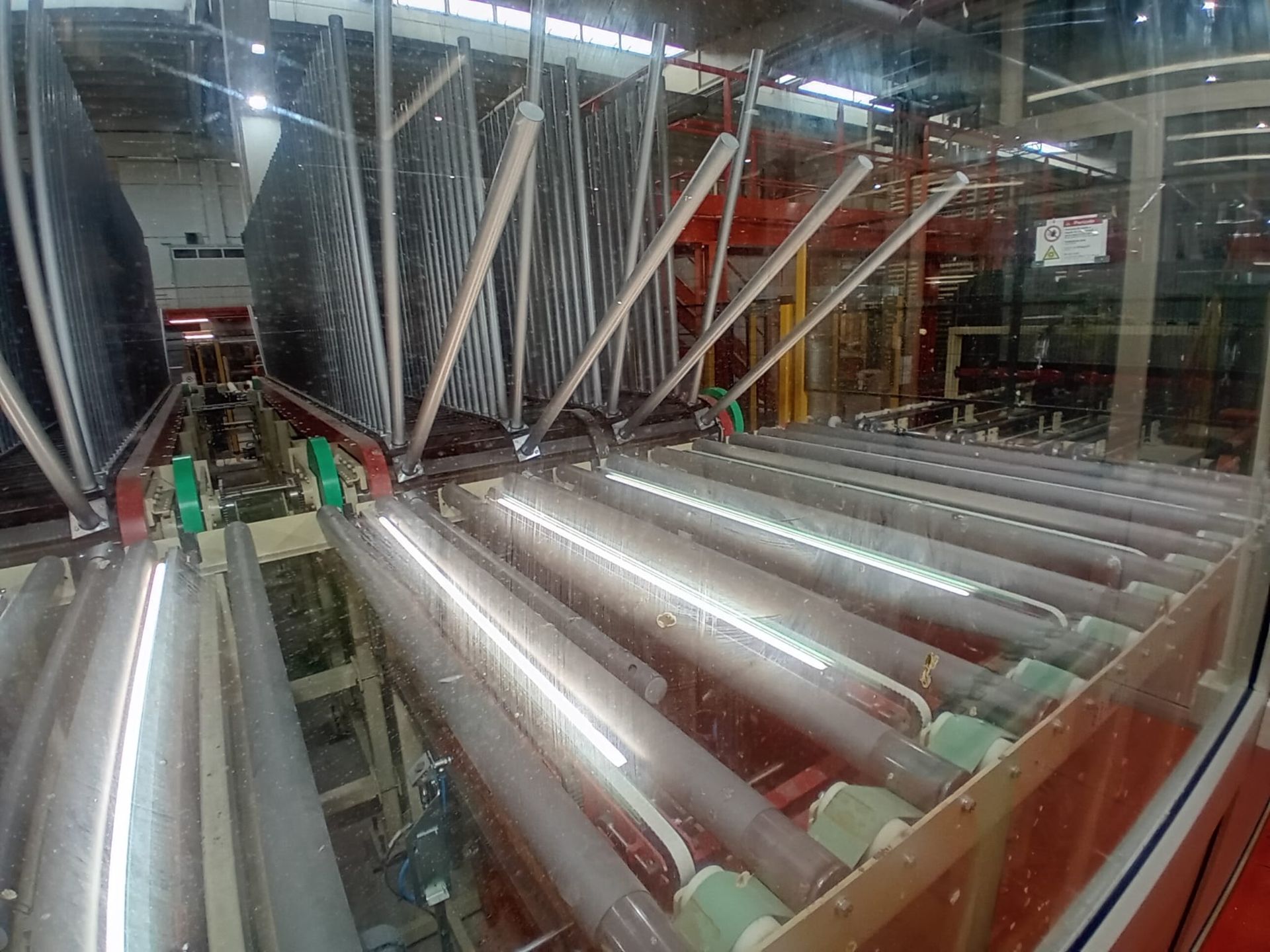 Sistema di trasporto industriale con rulli metallici e grandi serbatoi all'interno di una linea di produzione