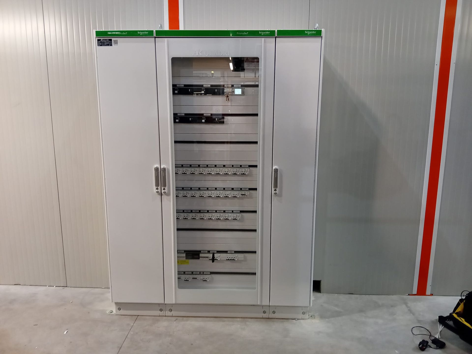 Armadio elettrico di controllo con ante centrali aperte in un locale industriale.