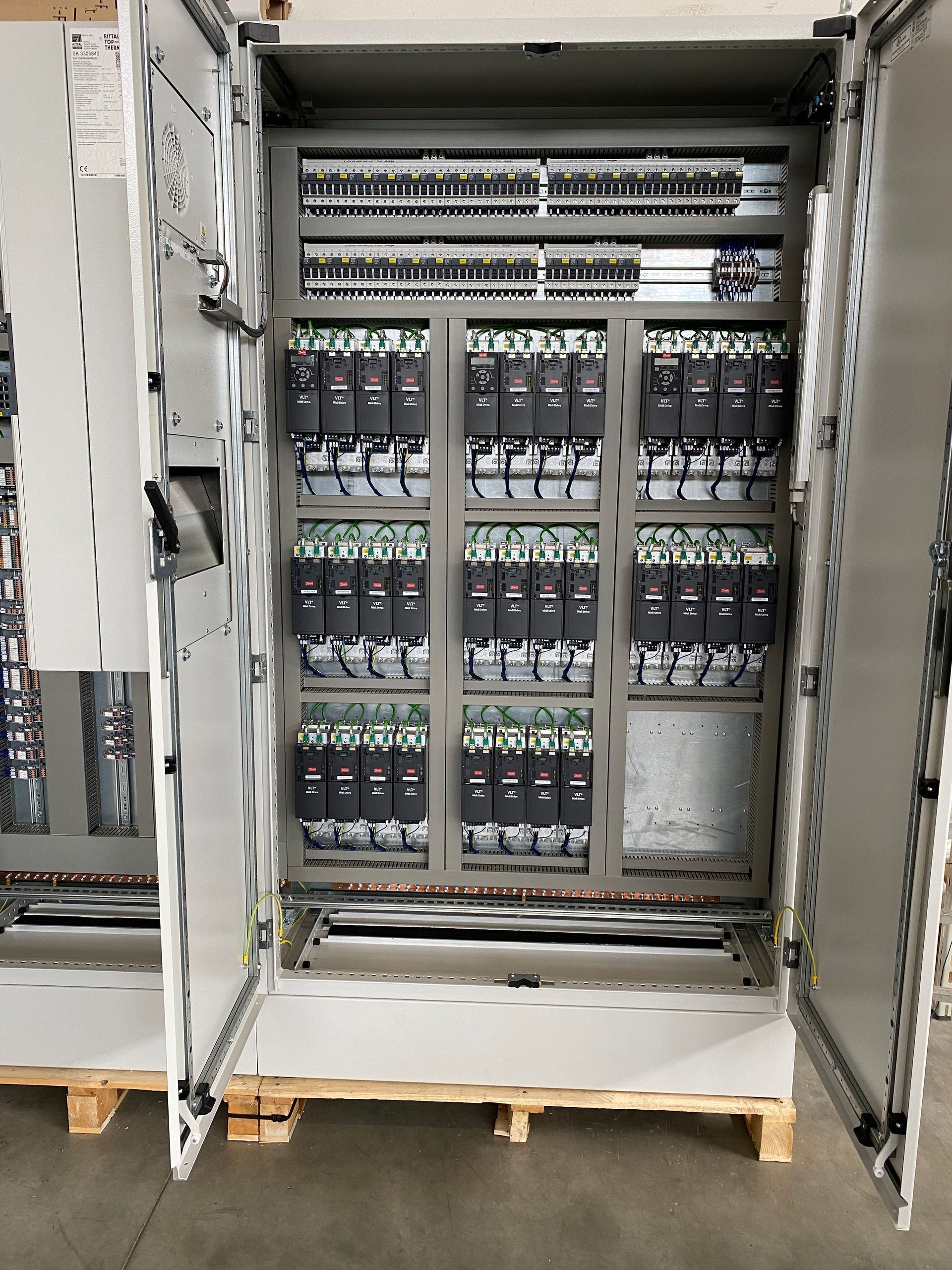 Armadio elettrico aperto con file di cavi e moduli all'interno di un contenitore industriale.