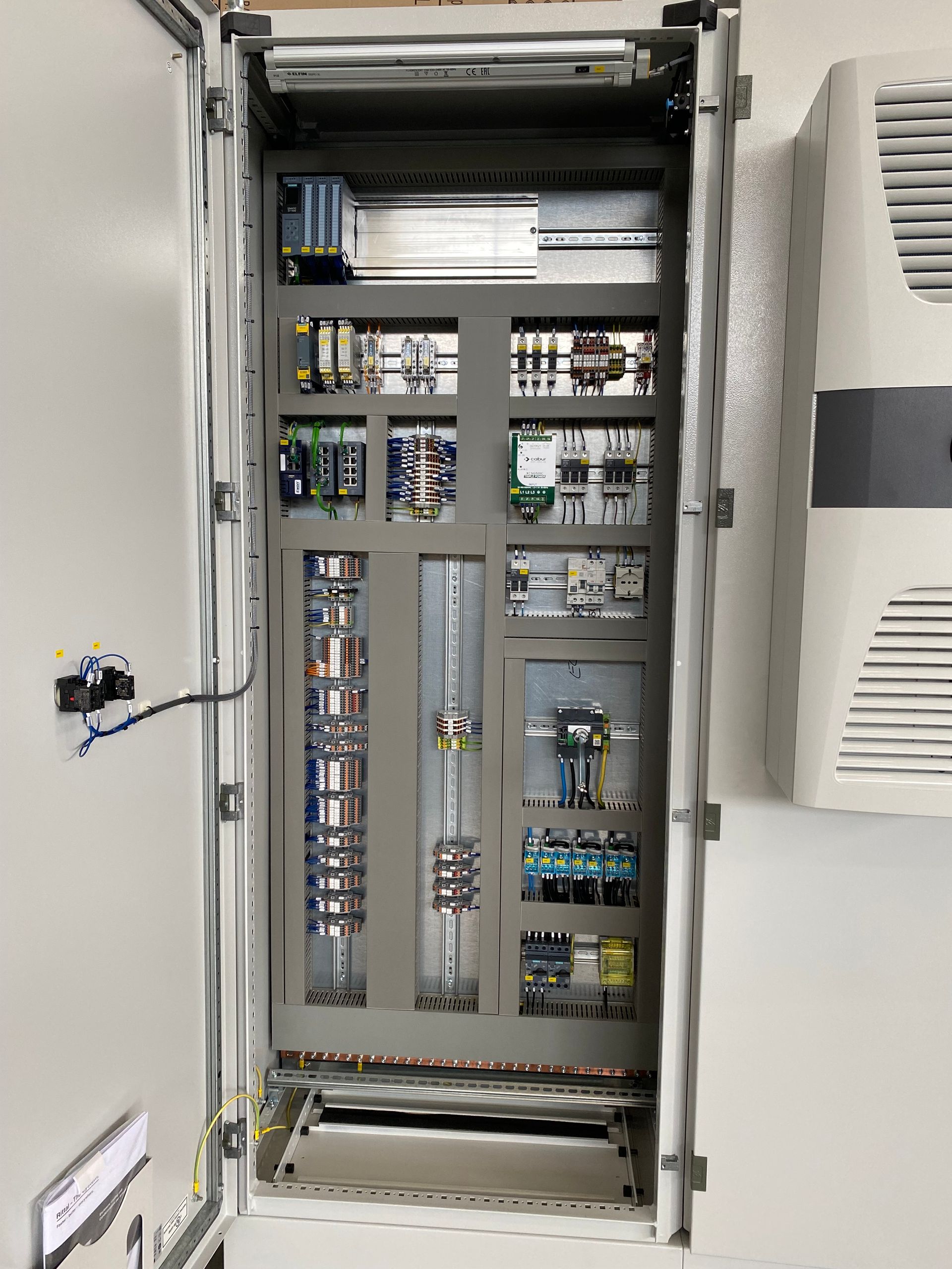 Armadio elettrico aperto con cablaggio, interruttori e componenti all'interno di una nicchia nel muro.