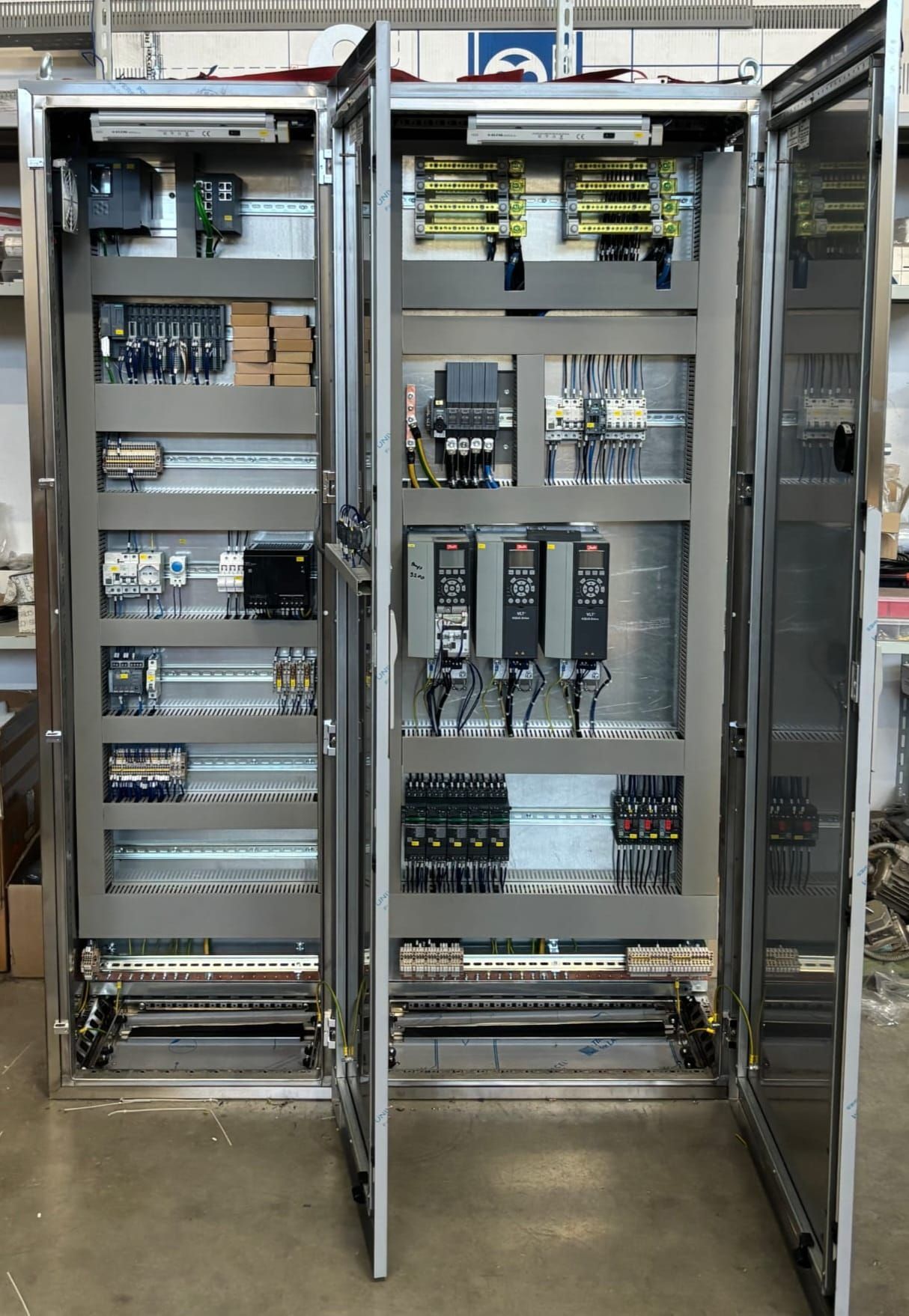 Armadi elettrici aperti con cablaggi, schede elettroniche e componenti all'interno di un'officina.