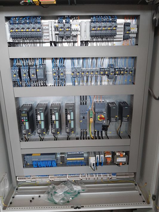 Armadio elettrico aperto con file di relè, cablaggi e moduli di circuito al suo interno.