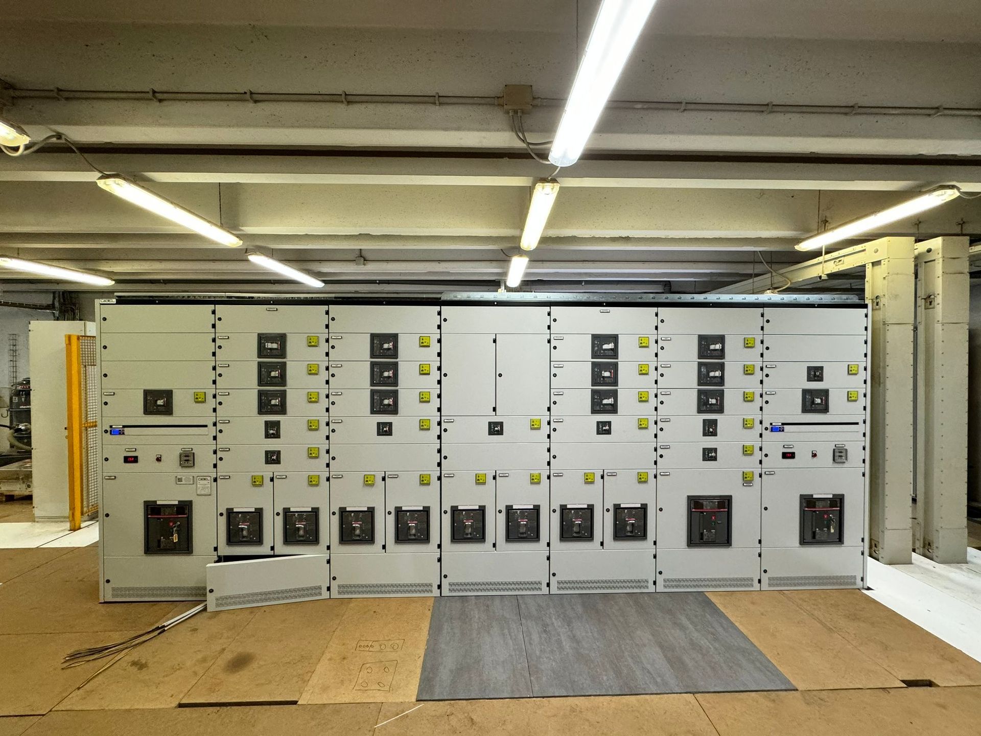 Armadi per quadri elettrici industriali in un locale tecnico in cemento con illuminazione a fluorescenza.