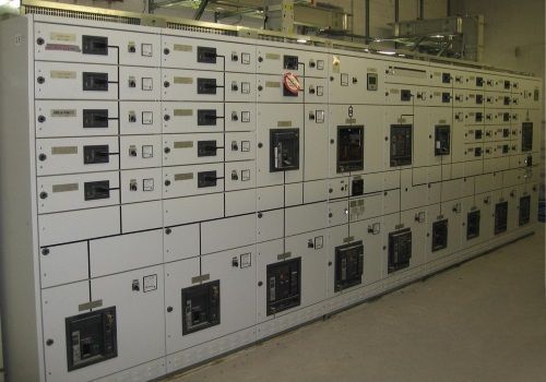Una fila di quadri elettrici industriali e interruttori in un locale tecnico.