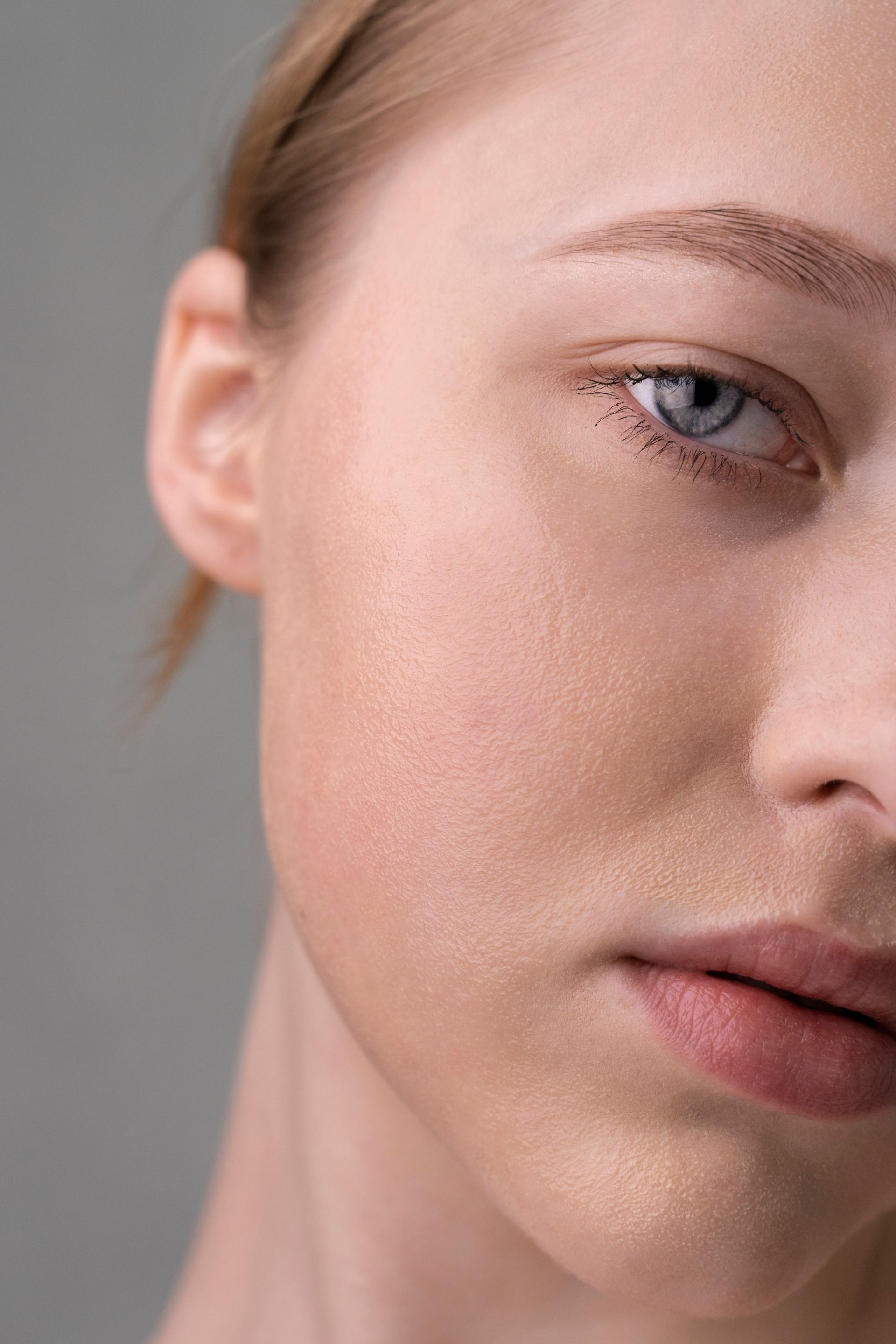 Un primer plano del rostro de una mujer con un fondo gris.