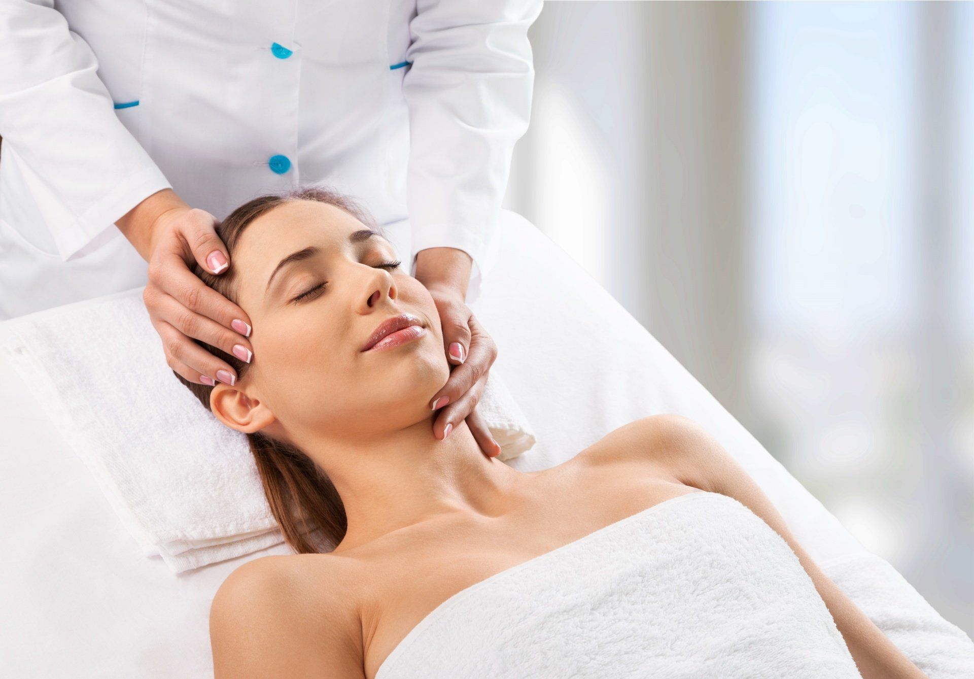 Una mujer está recibiendo un masaje facial en un spa.