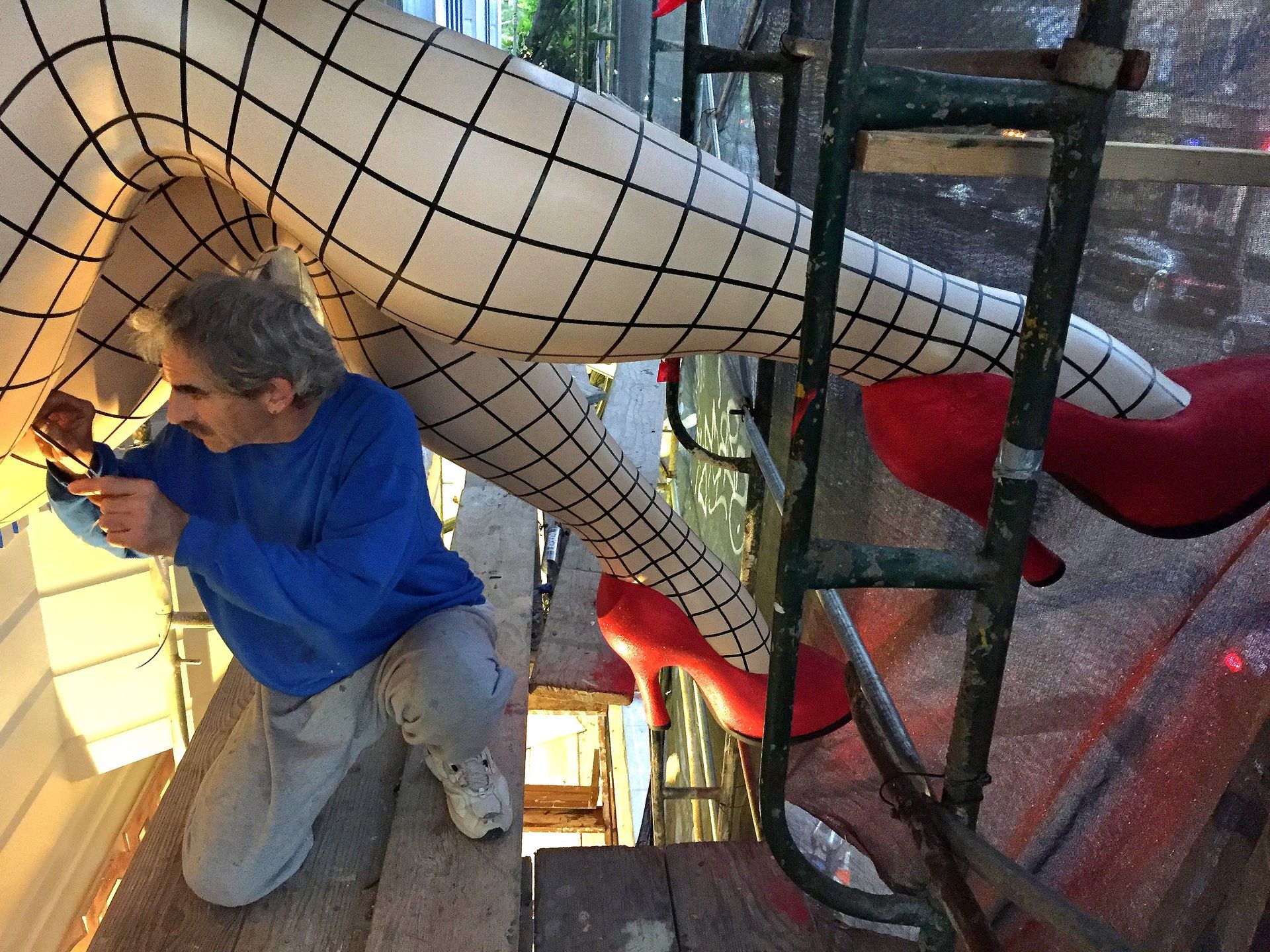 Person kneeling in blue hoodie in a rope play area with a large white netted structure and red seats