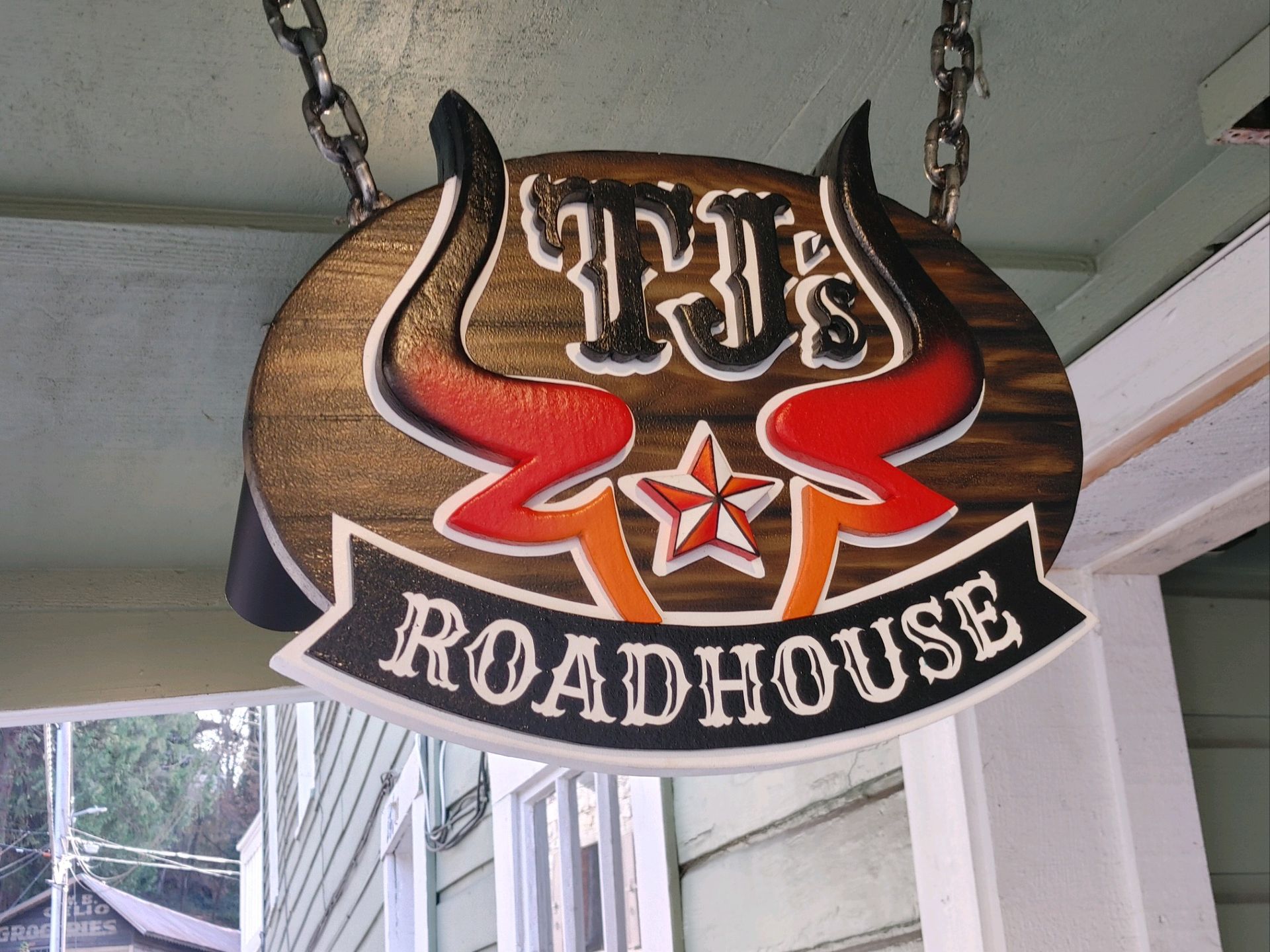 The Fish Roadhouse hanging sign with bull horns and red wings outdoors