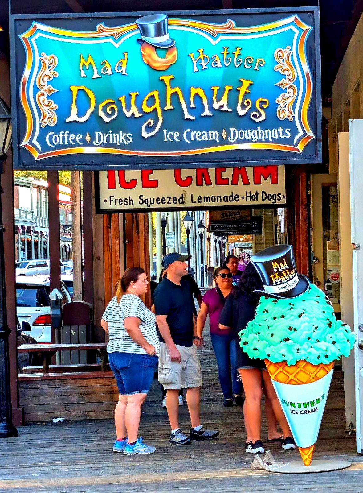 People outside a bright blue doughnut shop with an oversized ice cream cone sign
