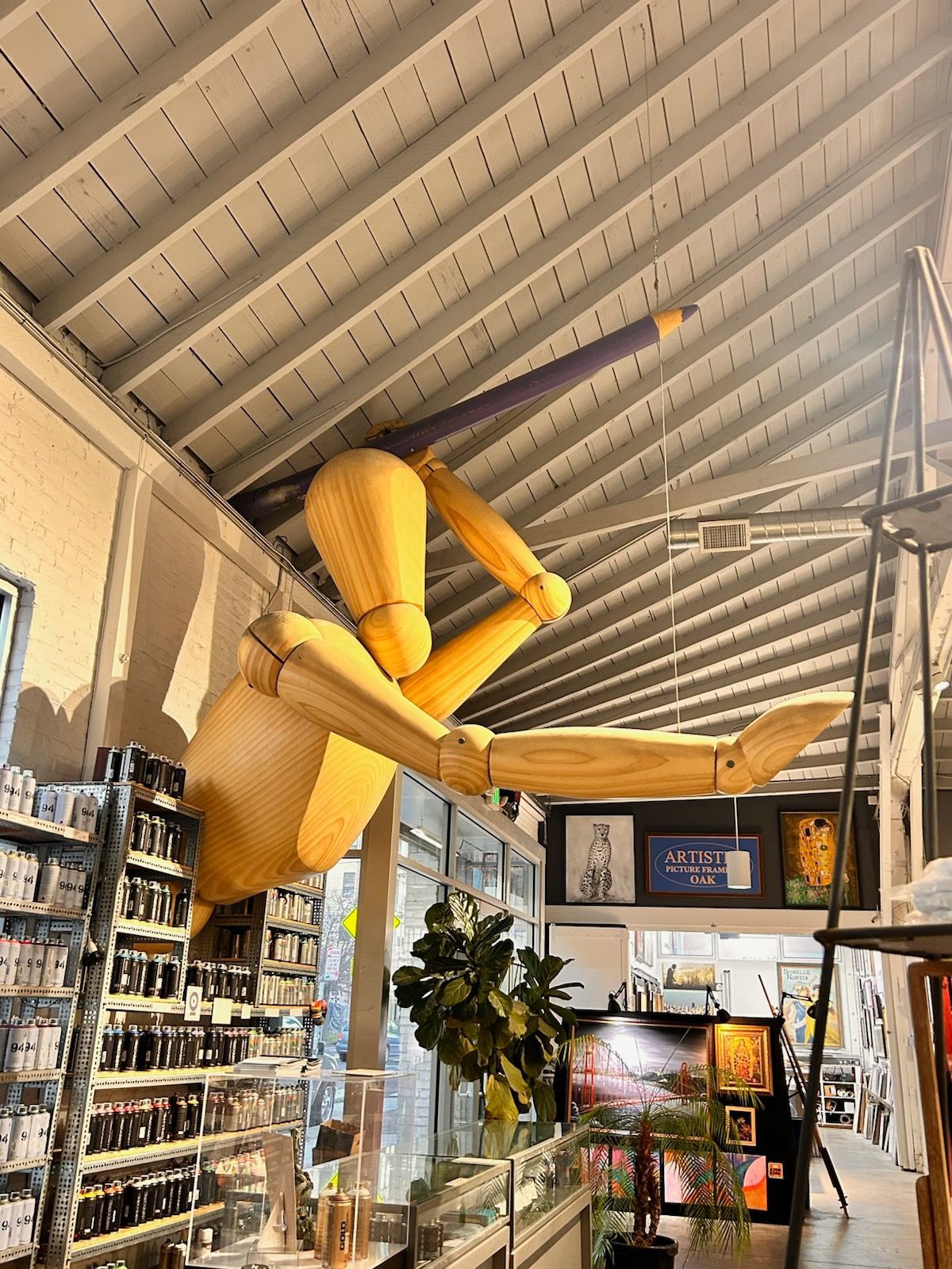 Indoor café with a giant yellow hanging puppet sculpture beneath a slanted ceiling