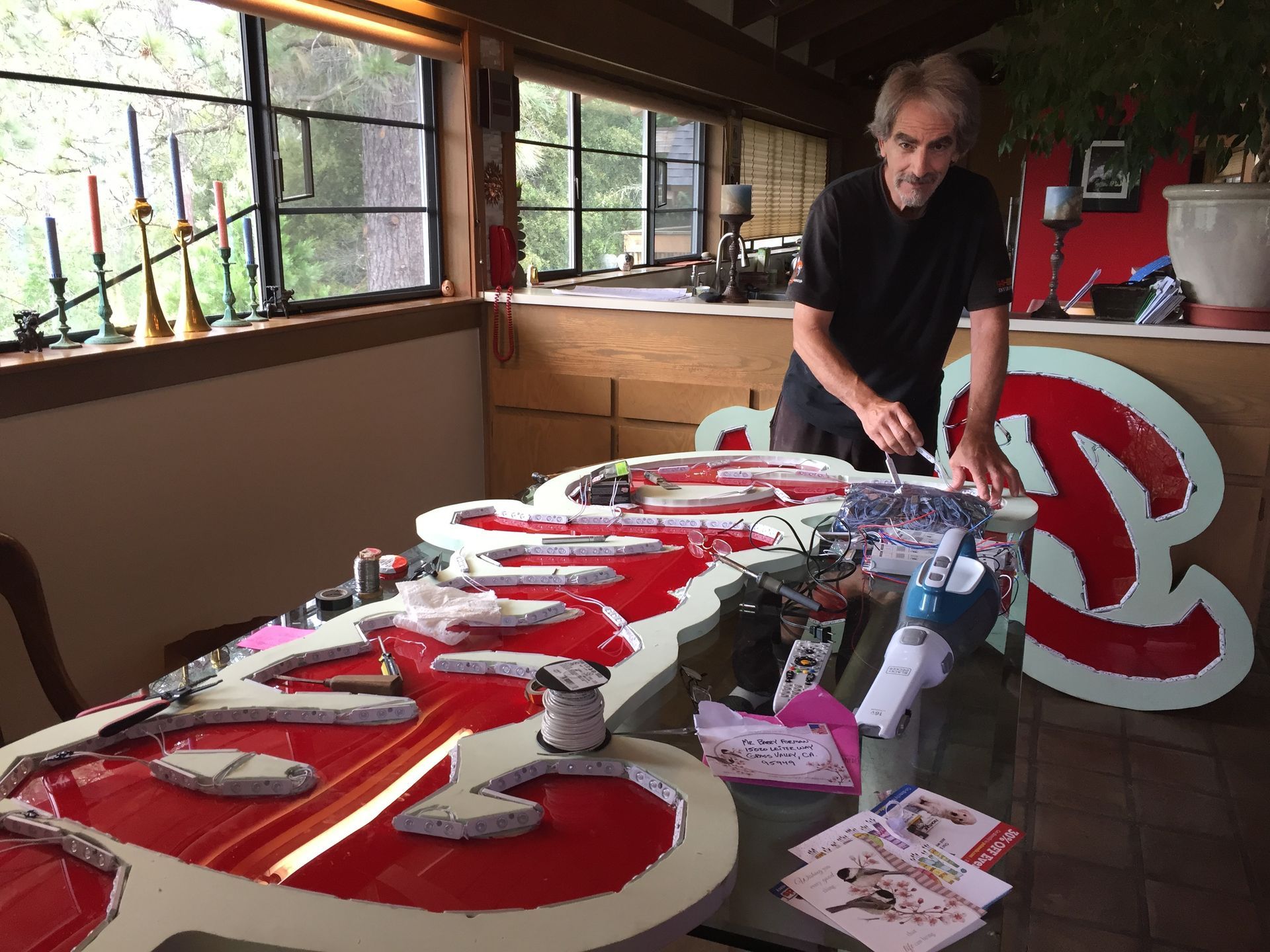 Person arranging large red-and-white letters on a table in a workshop room.