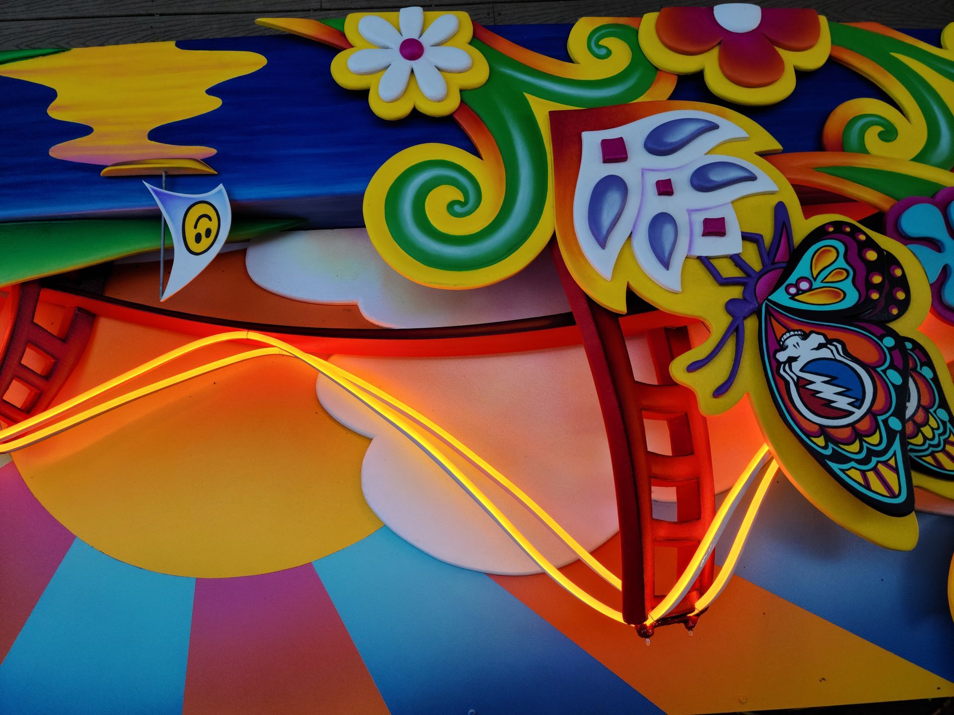 Bright abstract mural with colorful swirls, flowers, and a large orange sun-like shape.