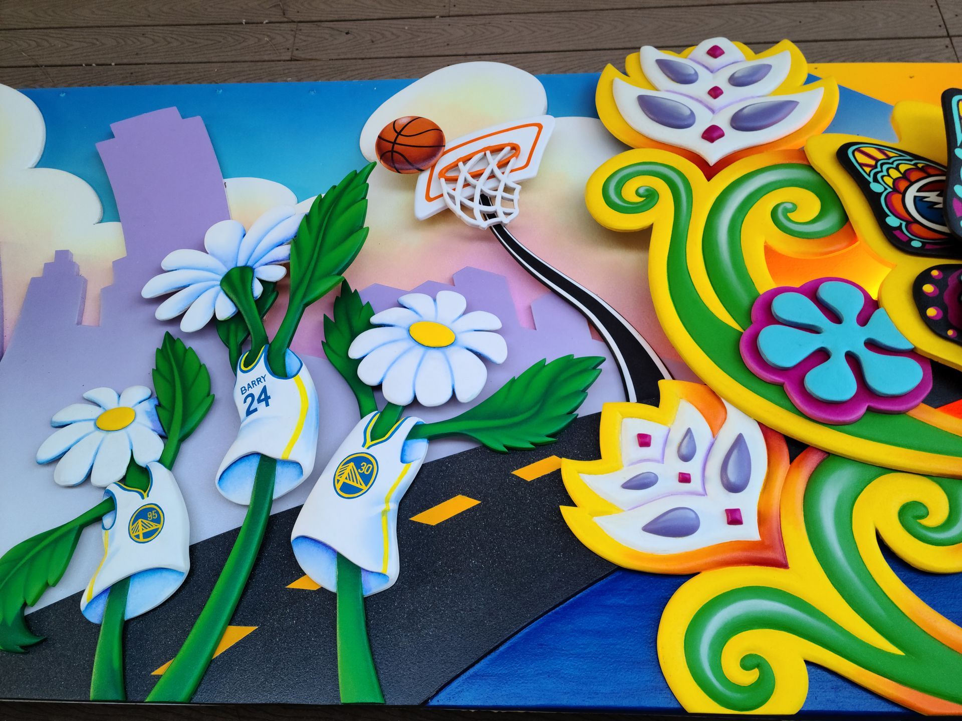 Colorful flower mural with daisies, a basketball hoop, and bright swirling patterns
