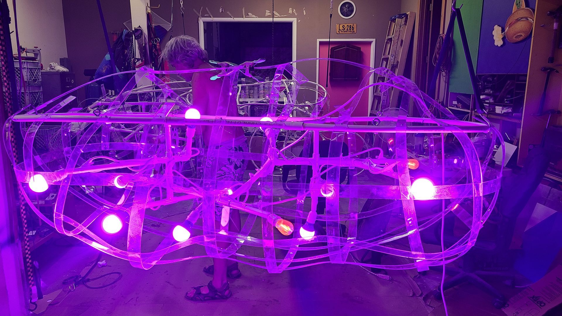 Purple-lit spherical art installation made of wire and LED lights in an indoor room