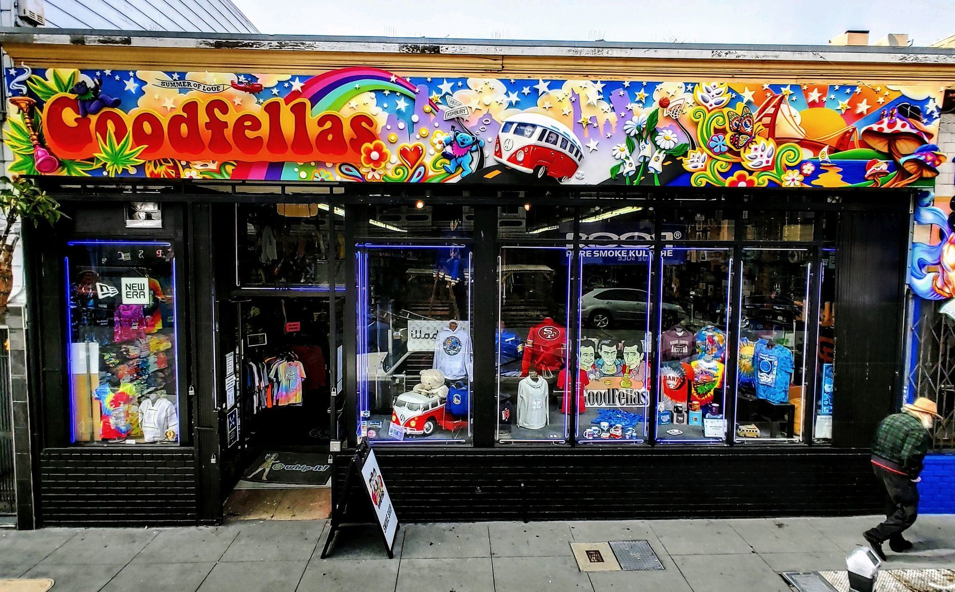 Colorful Godzilla toy store storefront with comic-style window displays and a sidewalk sign