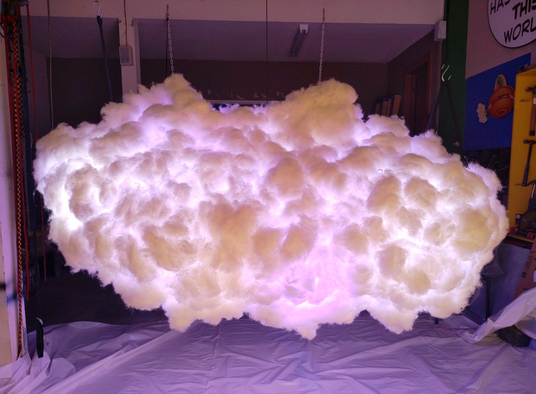 Large fluffy white cloud-like sculpture lit pink in an indoor room