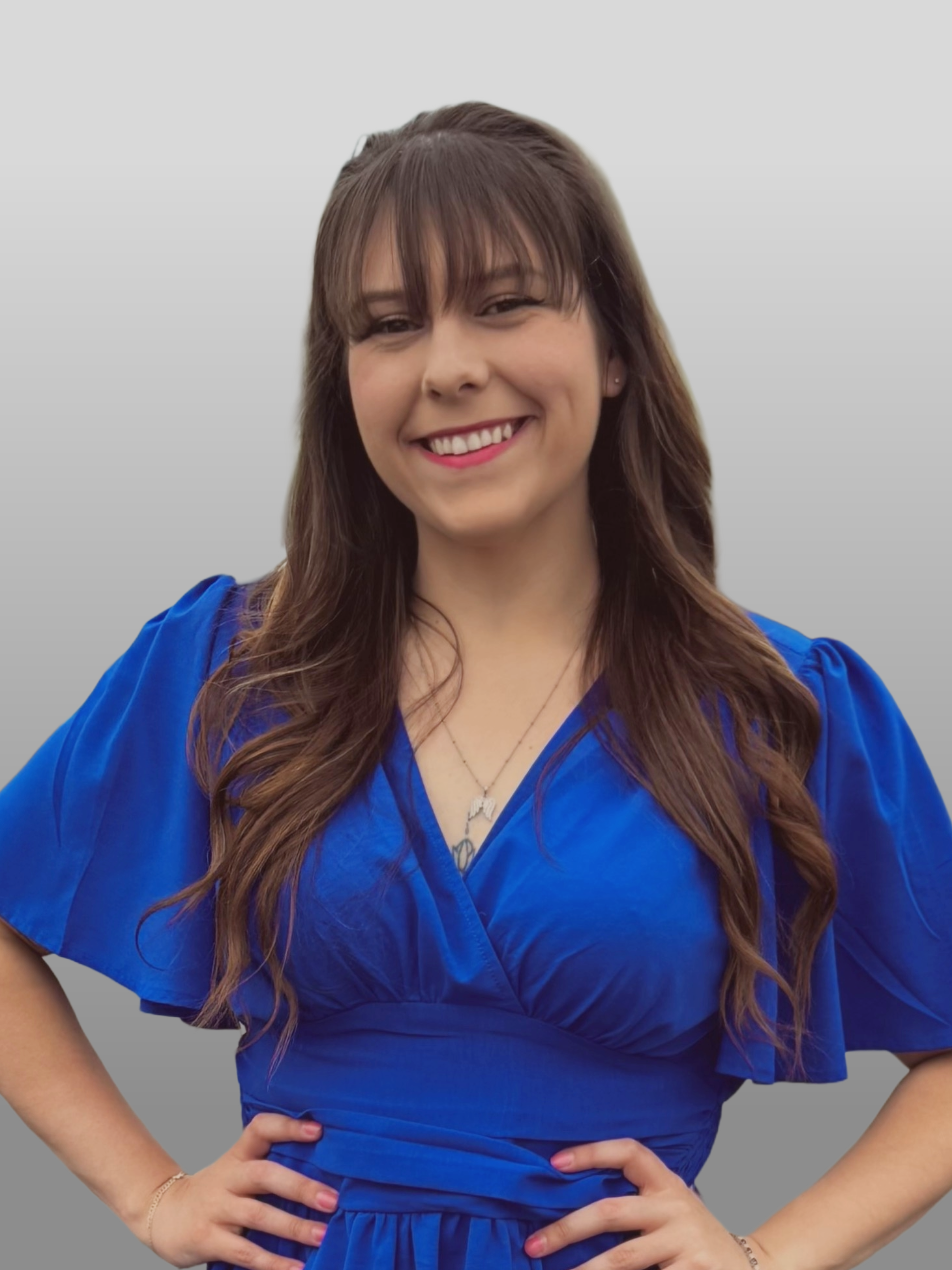 A woman in a blue dress is standing in a parking lot with her hands on her hips.