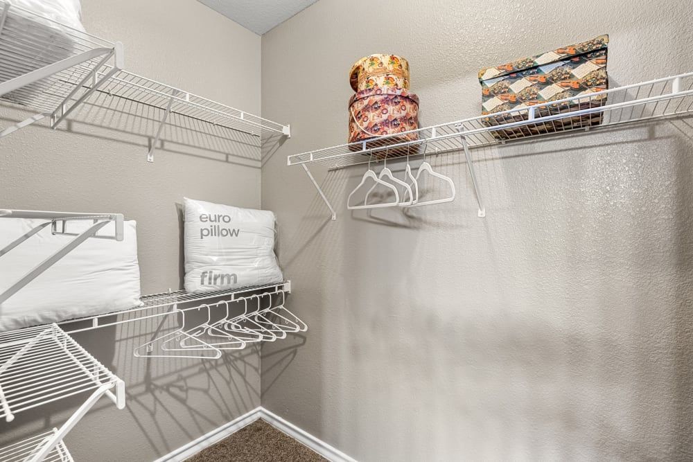 a walk-in closet with a lot of shelves and clothes hanging on them at Marquis at Deerfield in San Antonio, TX.